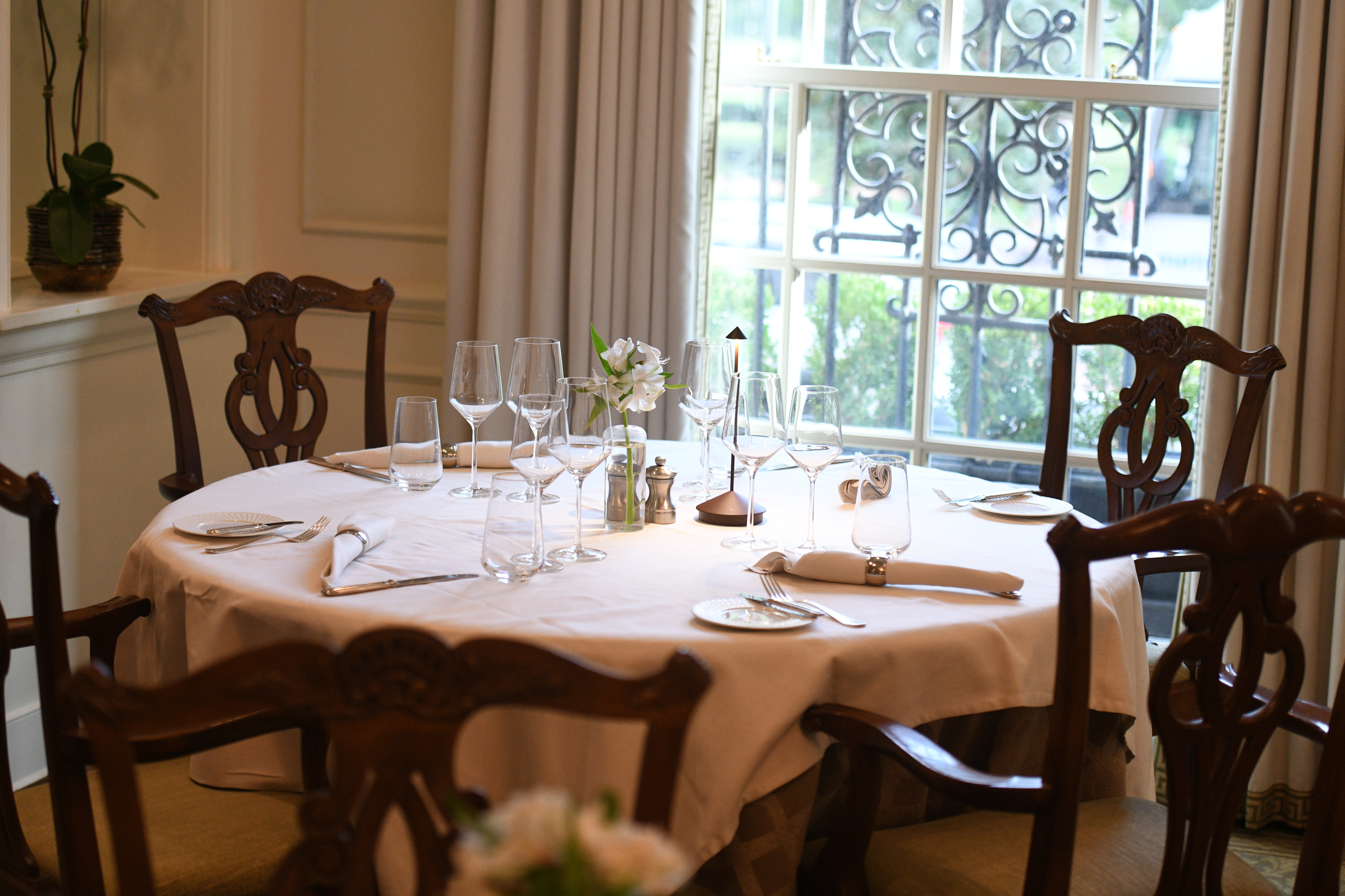 A formal dining table set with white tablecloth, wine glasses, flowers, and candle.