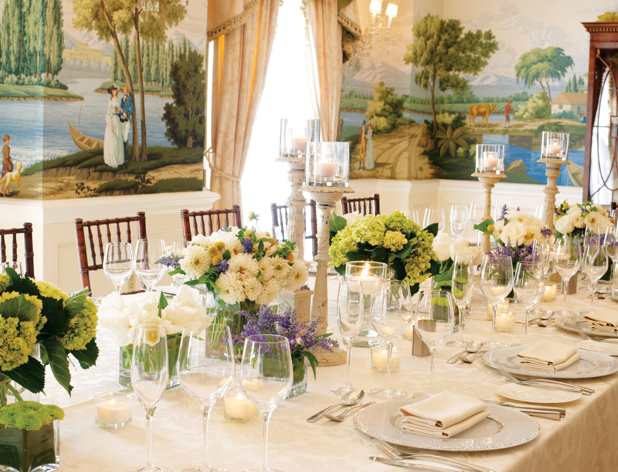 A long table set for a formal dinner with a white tablecloth, flowers, and candles.