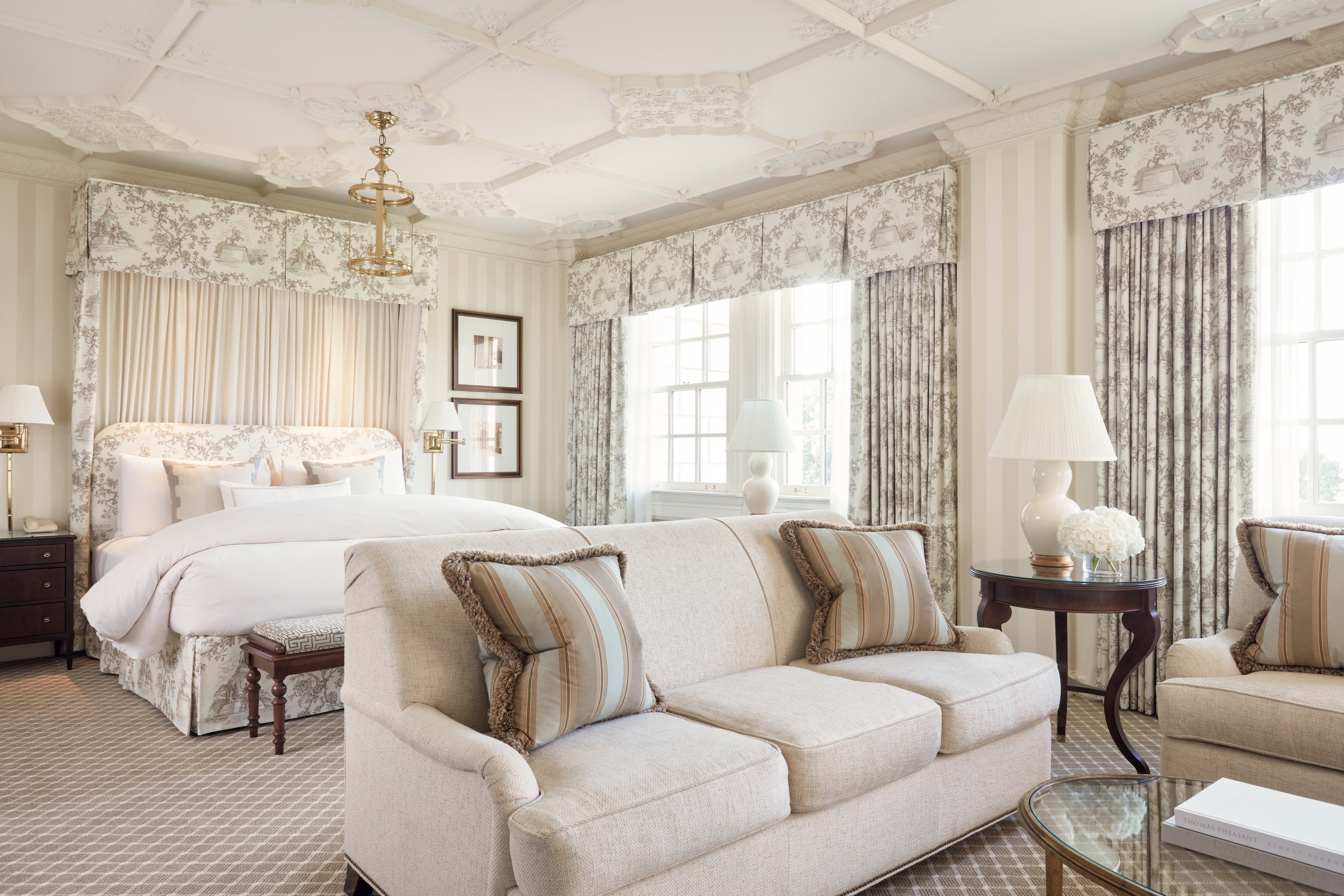 A luxurious hotel suite with a sitting area and a large bed