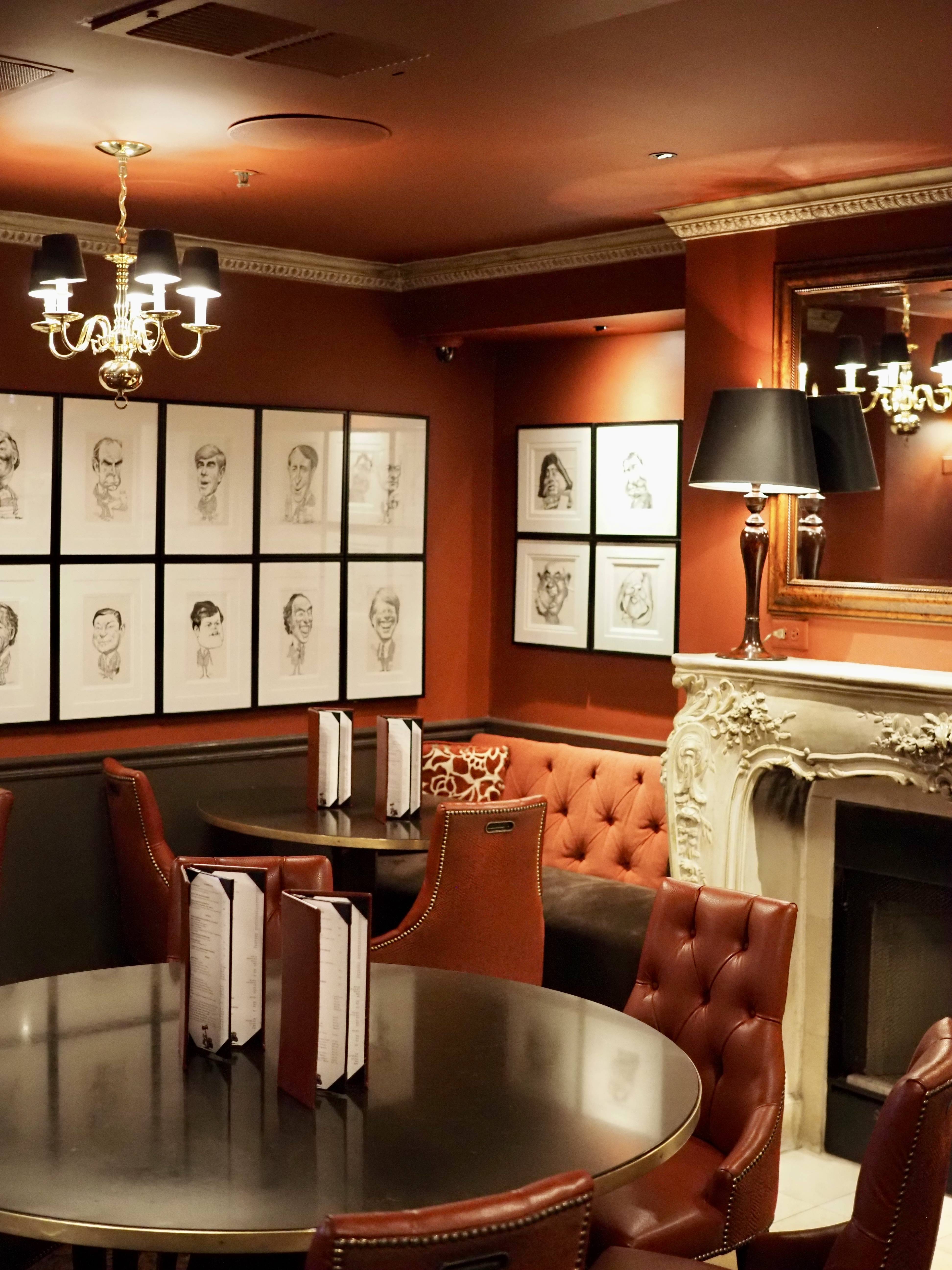 A luxurious lounge with a fireplace, chandelier, and artwork.