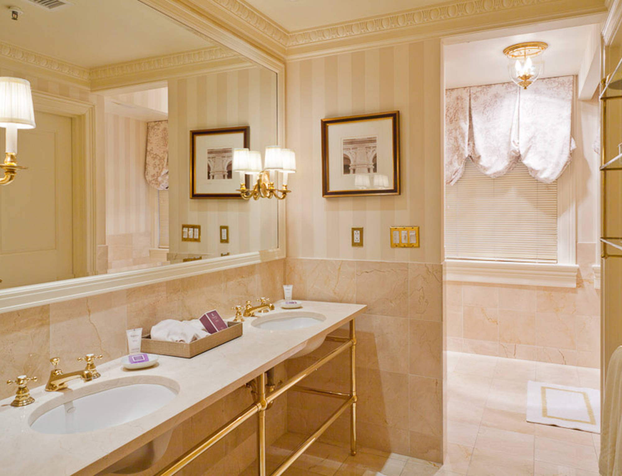 A luxurious bathroom with a double vanity, marble countertop, and gold fixtures.